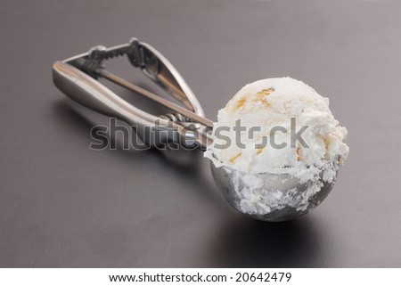 Ice cream with serving scoop against dark background.