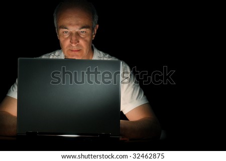 A male businessman working at his computer late at night
