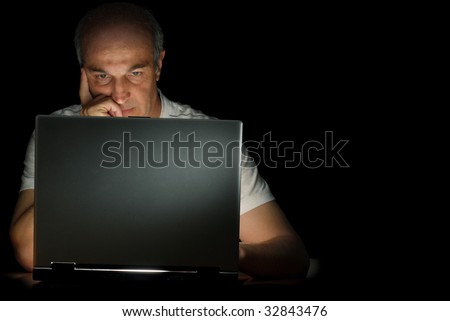A male businessman working at his computer late at night