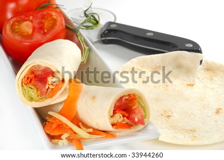 Veggies in tortilla wrap with tomatoes and white background