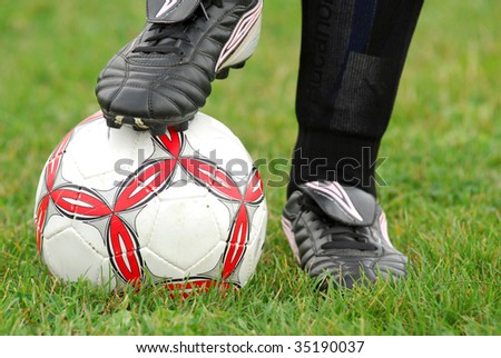Close-up image of soccer ball and cleats with grass background