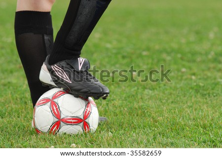 Close-up image of soccer ball and cleats with grass background