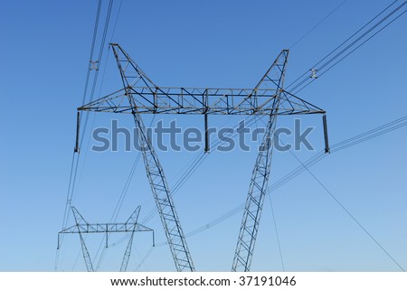 High voltage power line towers isolated against blue sky