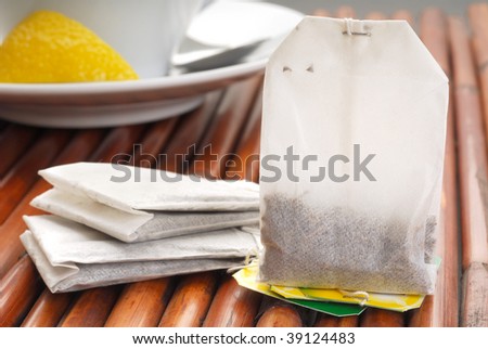 A tea bag with a cup of tea in the background