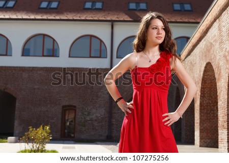 handsome girl dressed in red short skirt standing outside in urban landscape in a sunny day