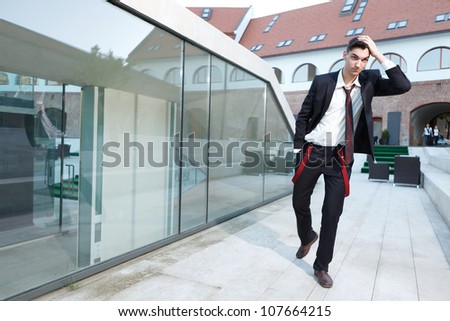 Handsome young hipster fashion male model wearing shirt and red braces posing outdoors