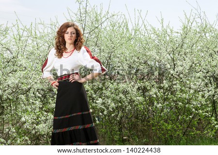 Girl in traditional outfit with white flower in background