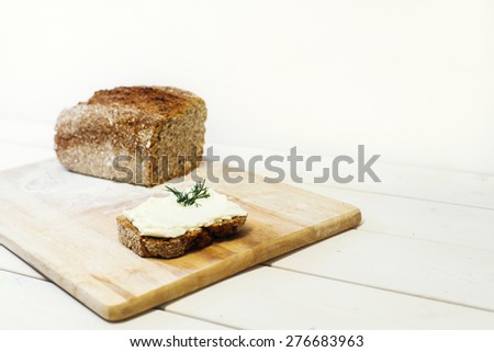 Bread lice with cream cheese on wood cutter on bright white table and white background