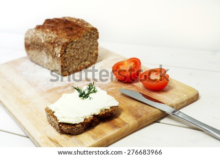 Bread lice with cream cheese and tomatoes on wood cutter on bright white table and white background