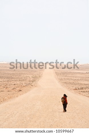 Lonely woman is walking on the desert road