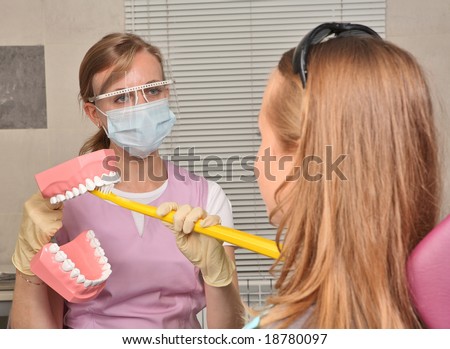 Dentist showing how to clean teeth with a model jaw and a big toothbrush