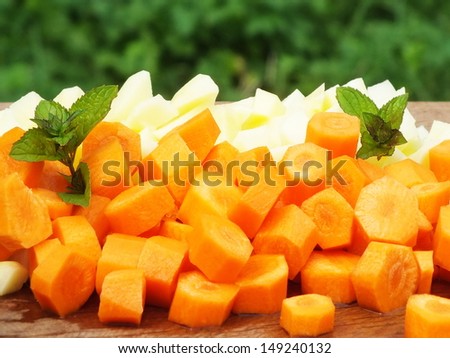 raw sliced potatoes and carrots on a oak board