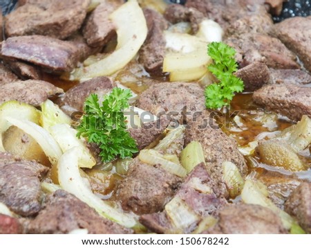 fried liver with apple and onion in a pan