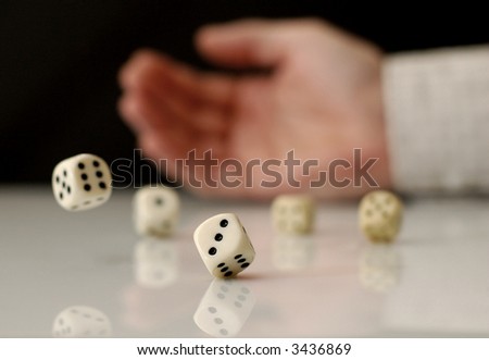 Hand rolling dices on white table, with reflection. Shallow depth of field.