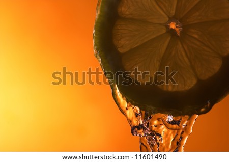 Lemon slice and water over orange background - back lit