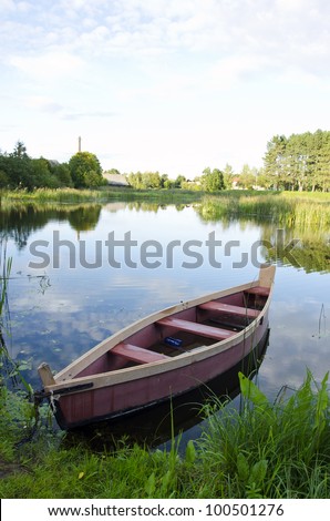 boat moored with chains at river shore. water transportation. green lake flora in summer.