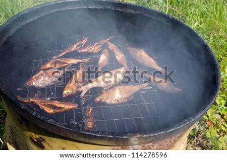 closeup of fish smoking for food in retro rusty barrel