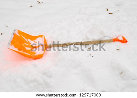 orange plastic snow clean tool lie rest on snowdrift in winter.