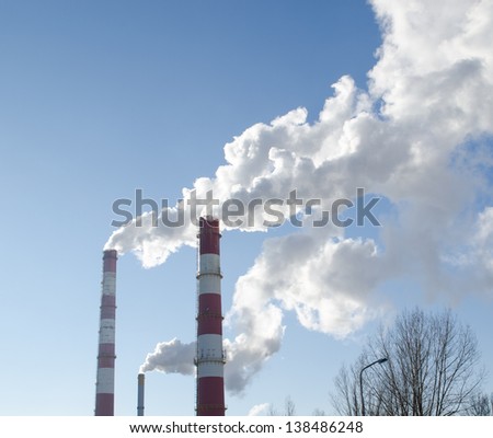 white smoke vapour rise from industrial factory chimneys on background of blue sky. boiler-house heating all city houses in winter.