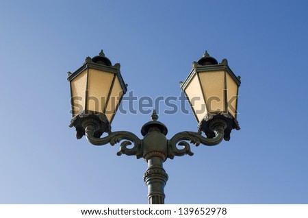 vintage iron lighting pole with twin double lamp lantern on background of dark blue sky.