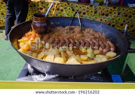 Potatoes, sausage and cabbage baked in a huge metal pan. Delicious organic meals in rural fair celebration.