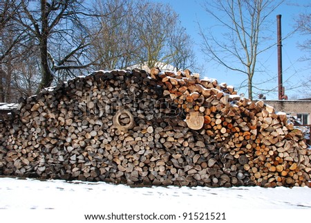 Snow covered firewood pile next to boiler house. Preparing for the cold season.