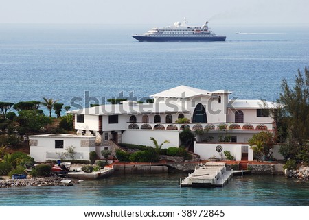 The view of a house built on the narrow tip of Paradise island and the cruise ship in a background arriving to Nassau, The Bahamas.