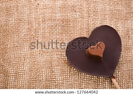 greeting card for Valentine\'s Day with chocolate heart symbol with needle on fabric sack texture background