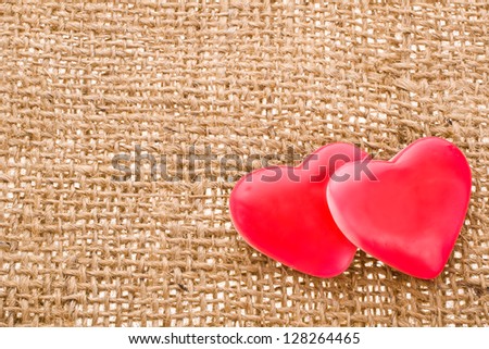 with two red hearts symbol of candy with  needle on fabric sack texture background
