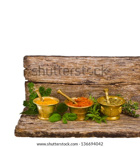 Spices for the kitchen - dry oregano, saffron and mix in three copper mortar and fresh sprigs of herbs isolated on white background