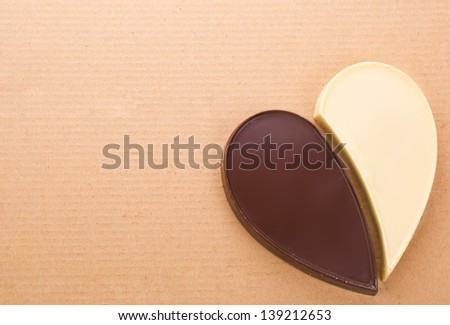 Heart figure two halves of a black and white chocolate on the background of cardboard