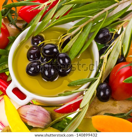 Topic cuisine - olive oil in a white saucer framed vegetables and herbs