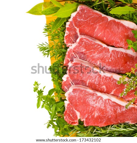 fresh meat - fresh steaks on a yellow mat, fresh herbs and vegetables isolated on white background