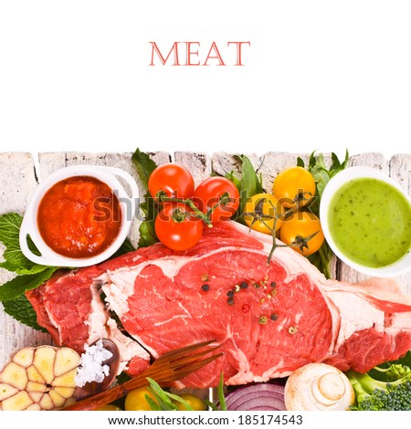 meat, a large piece of fresh meat, beef, to be on the old white boards,  decorated with greens and vegetables and bowls with sauces  isolated on white background
