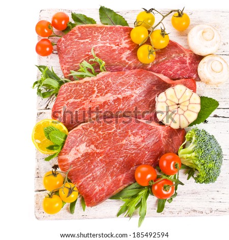meat, a large piece of fresh meat, beef, to be on the old white boards, decorated with greens and vegetables and bowls with sauces isolated on white background