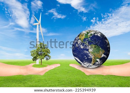 Green Earth concept,hand holding tree with wind turbine and earth against green field and blue sky background.Elements of this image furnished by NASA