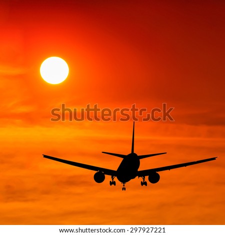 Silhouetted commercial airplane flying at sunset