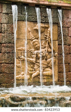 Fairy in low relief statue cut out as jig saw image and water fall in front of.