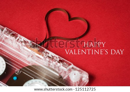 Valentines day card - audio cassette with magnetic tape in shape of heart on red background