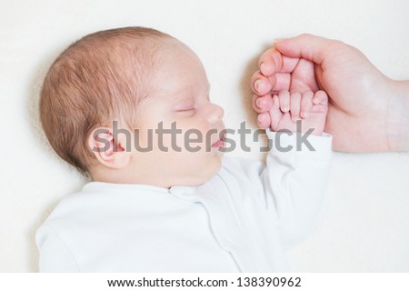 mother holding tiny hand of her cute month old baby
