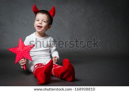 cute little boy with devil horns and red star, gray background