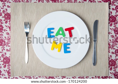 Concept: healthy food and diet - word EAT ME on a white plate