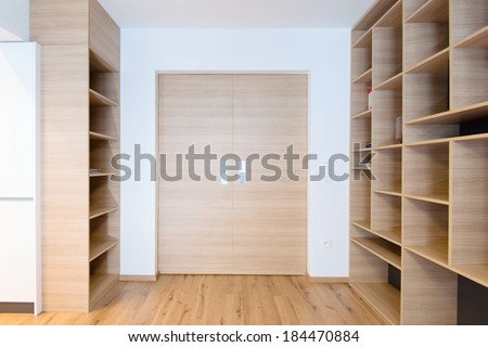 empty bookshelves and closed door in empty apartment