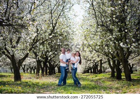 Young happy family in cherry blossom spring garden