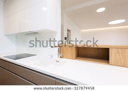 Sink with tap and induction cooker on white worktop of contemporary kitchen