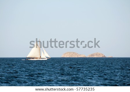 small yacht sailing on the sea with island in the background