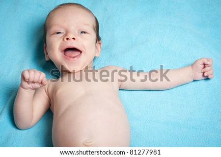 happy smiling baby boy lying on blue blanket