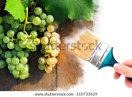 Hand with brush painting grapes on a wooden barrel