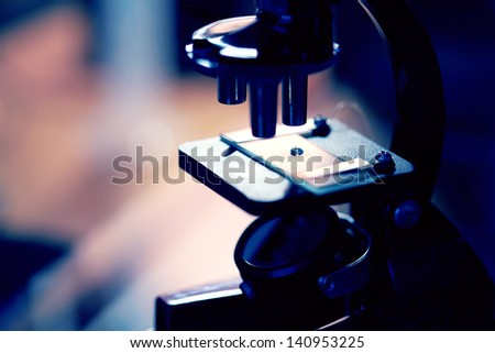 Microscope with biological material in laboratory. Blue tone.