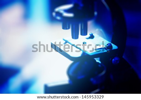 Microscope with biological material in laboratory. Blue tone.
